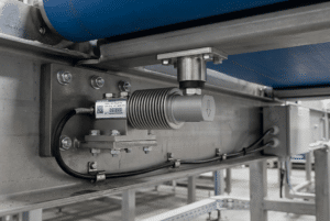 Bending beam load cell mounted under a conveyor belt idler frame showing installation and cable routing